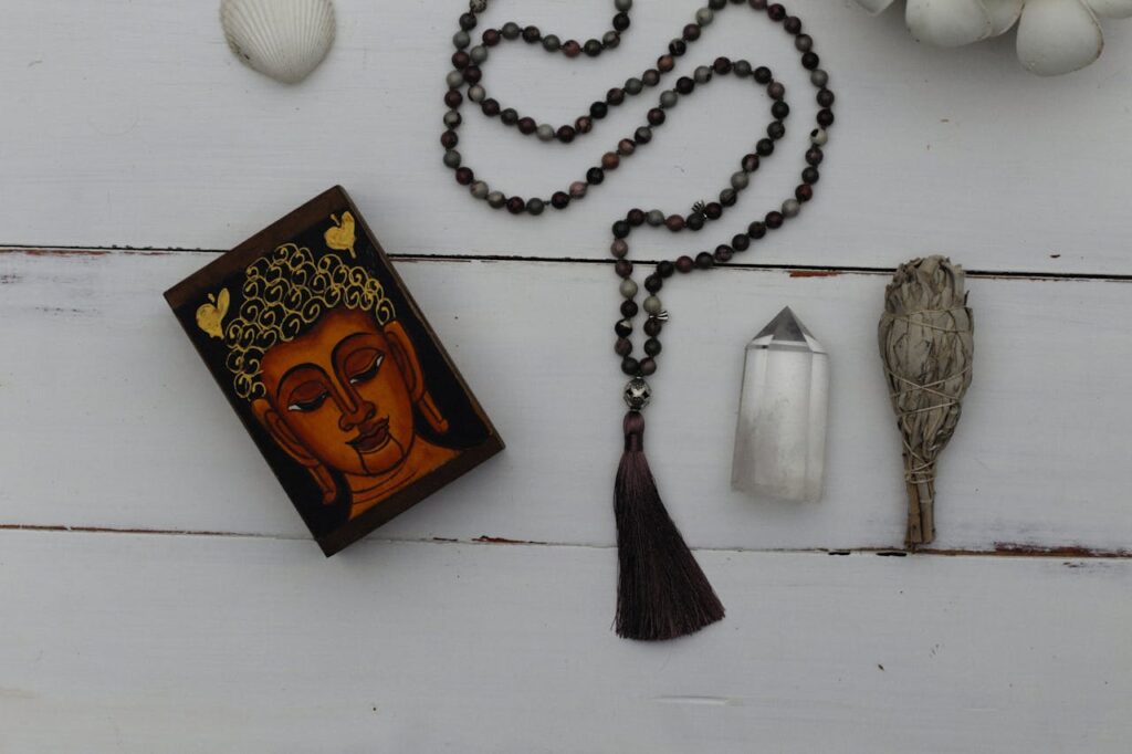 A Prayer Beads and Holy Book Beside a Crystal and Sage