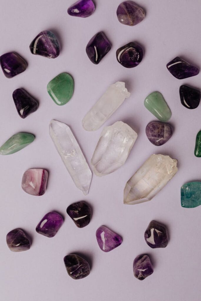 Top view of multicolored polished amethyst jade malachite and colorless rock crystal arranged on gray table in studio